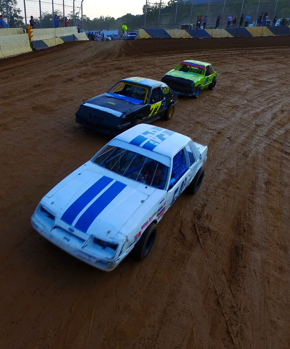 Stock cars racing three-wide through the clay corner at Path Valley Speedway
